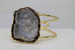 Gold-plated cuff bracelet with natural grey geode slice.