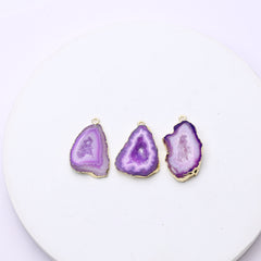 Vibrant purple agate geode charms with rough druzy interiors and connector loops