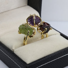 Triple gemstone adjustable ring featuring raw purple, green, and red stones.