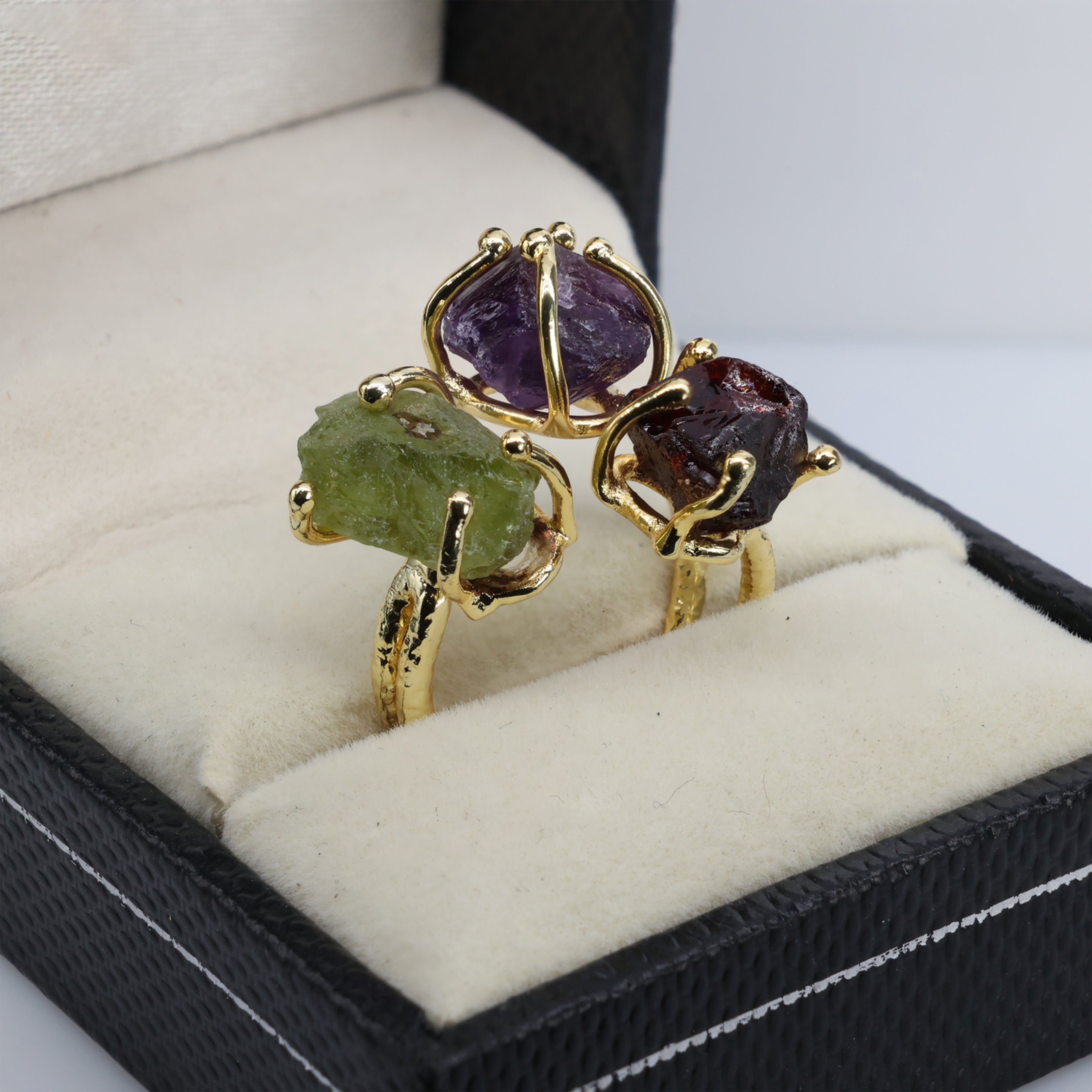 Triple gemstone adjustable ring featuring raw purple, green, and red stones.